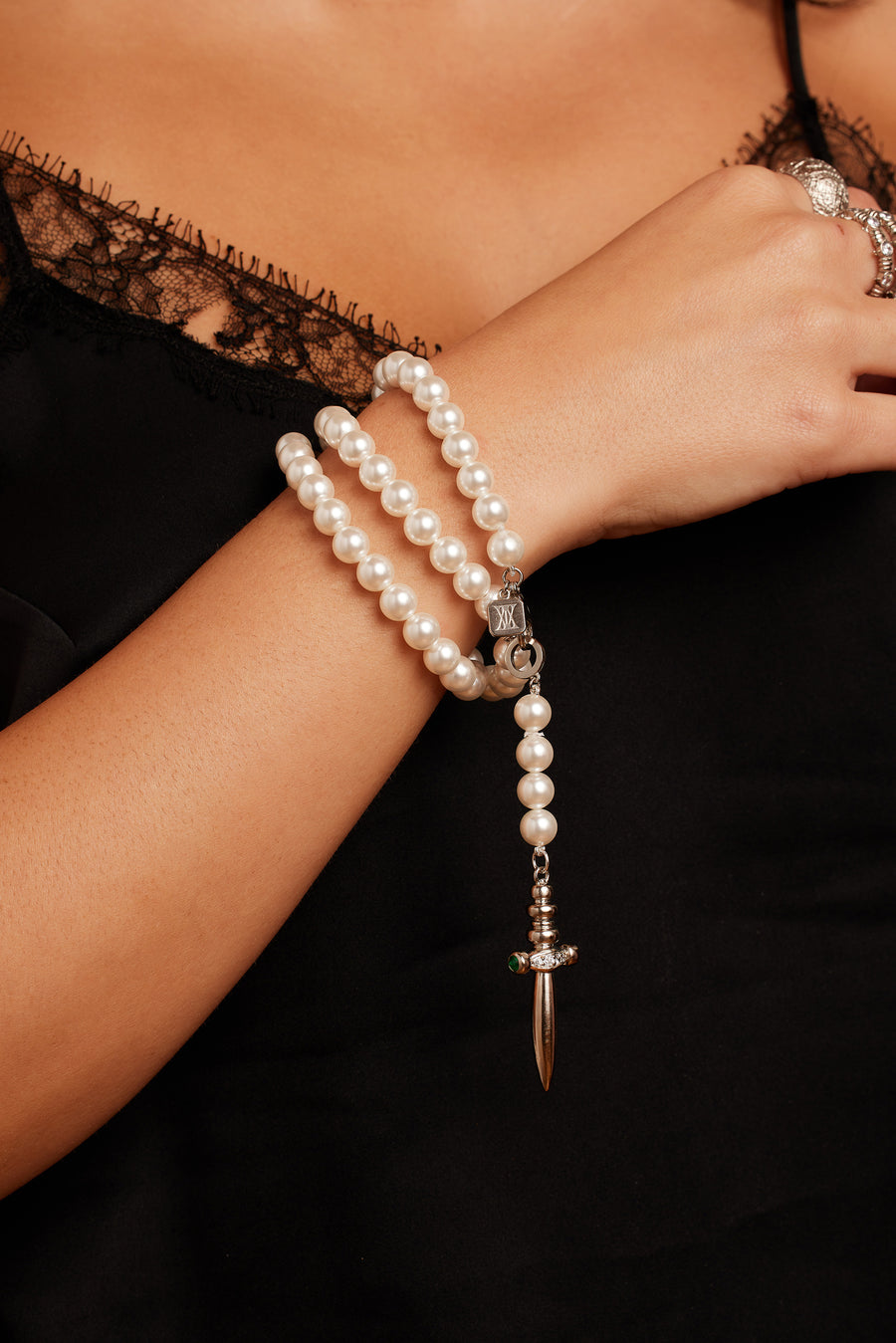 Woman wearing the Romeo Romeo Dagger Necklace in gold, wrapped around her wrist as a bracelet.